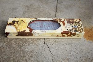 A handmade jewelry box wrapped in dried leaves with a corroded copper screen for a window into the box