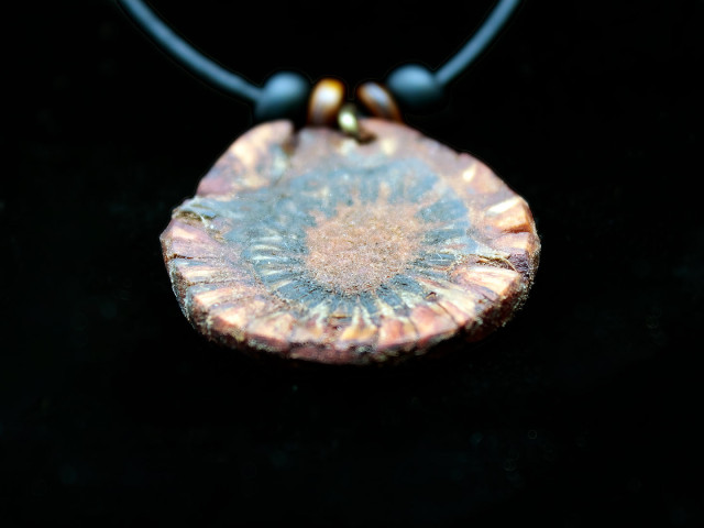 Extreme close-up of pinecone pendant against black background